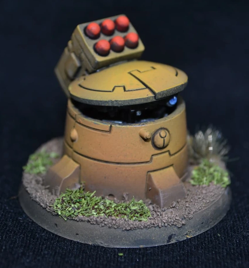 Detail: Tau Geschütz in gelbem Farbschema mit roten Raketen und blauem Sensor auf begrünter Base
