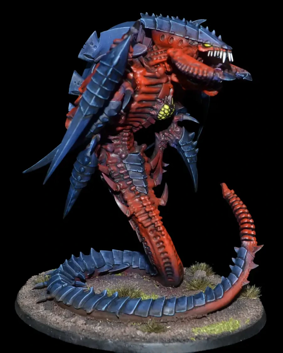 Detail: Trygon mit rotem Körper, blauem Chitinpanzer und langem eingerolltem Schwanz auf felsiger Base